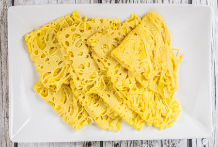 Malaysian dish Net Pancake or locally known as Roti Jala on white plate over wooden background