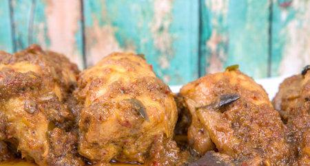 Malaysian dish Rendang Ayam or dry curry chicken in a white plate over wooden backgroundの写真素材