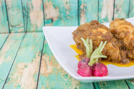 Malaysian dish Rendang Ayam or dry curry chicken in a white plate over wooden backgroundの写真素材