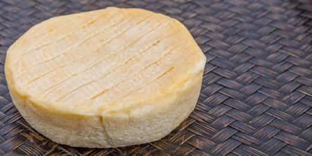 Round cheese on wicker backgroundの写真素材