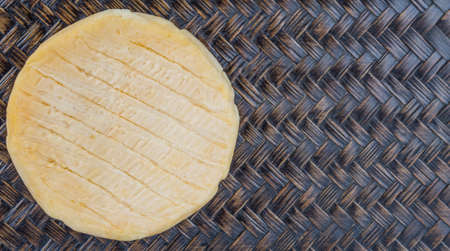 Round cheese on wicker backgroundの写真素材