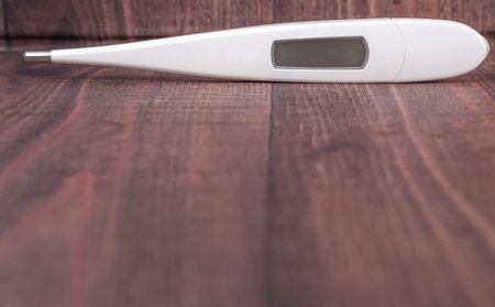 Medical thermometer over wooden background