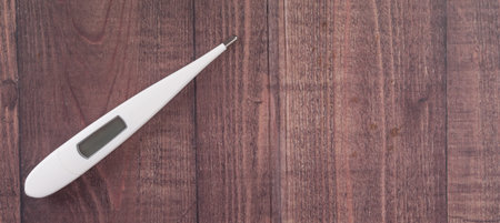 Medical thermometer over wooden background