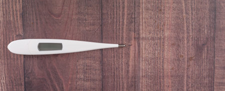 Medical thermometer over wooden background