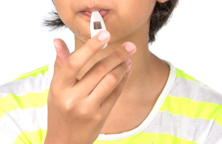 Young girl checking her body temperature with a medical thermometer