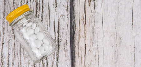 Medicinal pills in a glass bottle over wooden background