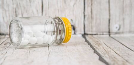 Medicinal pills in a glass bottle over wooden backgroundの写真素材