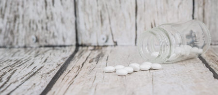 Medicinal pills in a glass bottle over wooden backgroundの写真素材