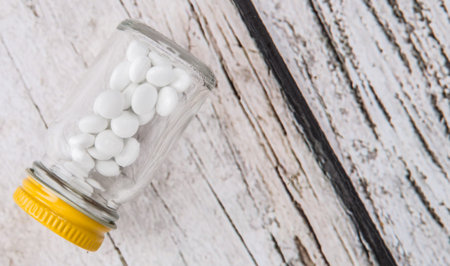 Medicinal pills in a glass bottle over wooden background