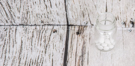 Medicinal pills in a glass bottle over wooden backgroundの写真素材