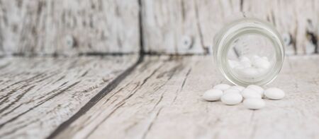 Medicinal pills in a glass bottle over wooden backgroundの写真素材