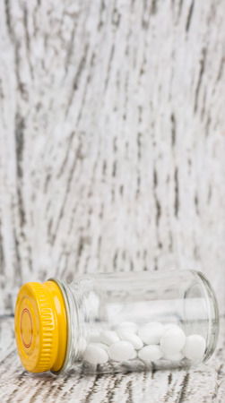 Medicinal pills in a glass bottle over wooden backgroundの写真素材