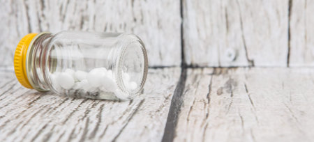 Medicinal pills in a glass bottle over wooden backgroundの写真素材
