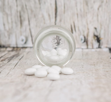 Medicinal pills in a glass bottle over wooden backgroundの写真素材