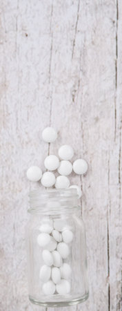 Medicinal pills in a glass bottle over wooden backgroundの写真素材