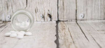 Medicinal pills in a glass bottle over wooden backgroundの写真素材