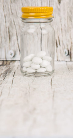 Medicinal pills in a glass bottle over wooden backgroundの写真素材