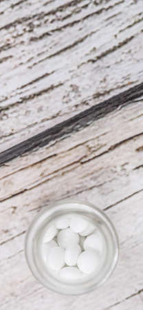 Medicinal pills in a glass bottle over wooden backgroundの写真素材