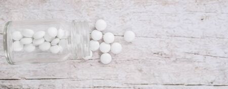 Medicinal pills in a glass bottle over wooden backgroundの写真素材