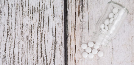 Medicinal pills in a glass bottle over wooden backgroundの写真素材