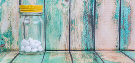 Medicinal pills in a glass bottle over wooden backgroundの写真素材