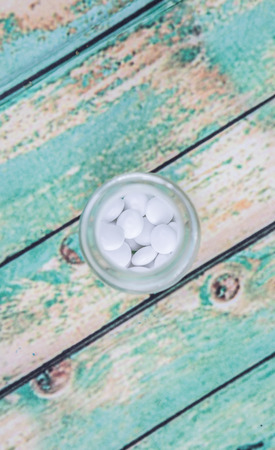Medicinal pills in a glass bottle over wooden backgroundの写真素材