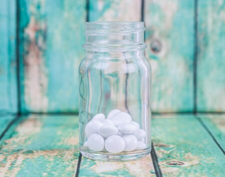 Medicinal pills in a glass bottle over wooden backgroundの写真素材
