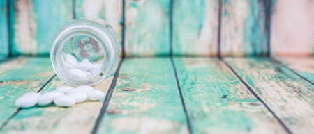 Medicinal pills in a glass bottle over wooden background