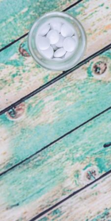 Medicinal pills in a glass bottle over wooden backgroundの写真素材