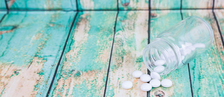 Medicinal pills in a glass bottle over wooden backgroundの写真素材