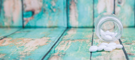Medicinal pills in a glass bottle over wooden backgroundの写真素材