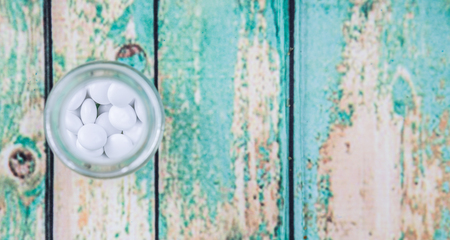 Medicinal pills in a glass bottle over wooden backgroundの写真素材