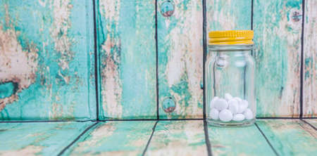 Medicinal pills in a glass bottle over wooden backgroundの写真素材