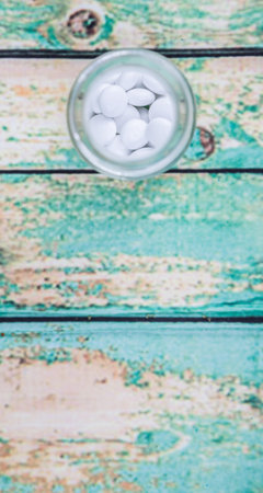Medicinal pills in a glass bottle over wooden background