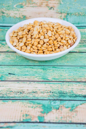 Raw Indian dhal in white bowl over wooden background