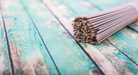 Dried raw soba noodle stick over wooden backgroundの写真素材
