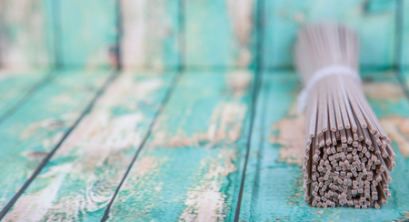 Dried raw soba noodle stick over wooden backgroundの写真素材