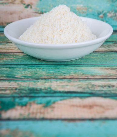 Grated cheese in white bowl over wooden backgroundの写真素材