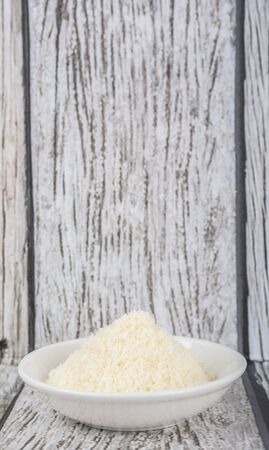 Grated cheese in white bowl over wooden backgroundの写真素材