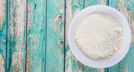 Grated cheese in white bowl over wooden backgroundの写真素材
