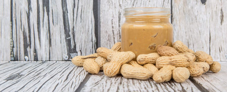 Peanut and peanut butter in a mason jar over wooden background