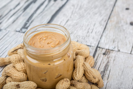 Peanut and peanut butter in a mason jar over wooden background
