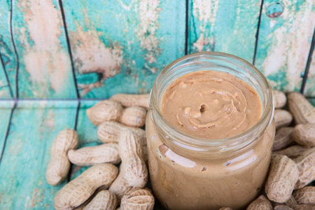 Peanut and peanut butter in a mason jar over wooden background