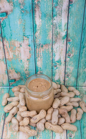 Peanut and peanut butter in a mason jar over wooden background