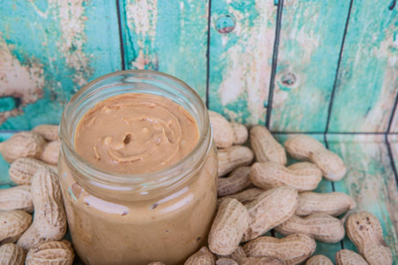 Peanut and peanut butter in a mason jar over wooden background