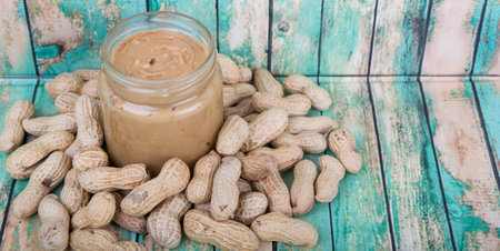 Peanut and peanut butter in a mason jar over wooden background