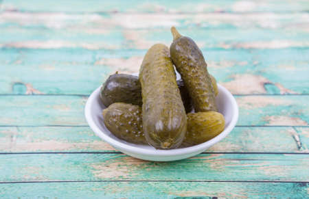 Dill pickles in a white bowl over wooden backgroundの写真素材