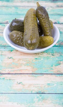Dill pickles in a white bowl over wooden backgroundの写真素材