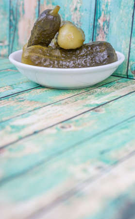 Dill pickles in a white bowl over wooden backgroundの写真素材