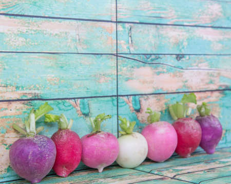 Pink, dark red, red, and purple radish over wooden backgroundの写真素材